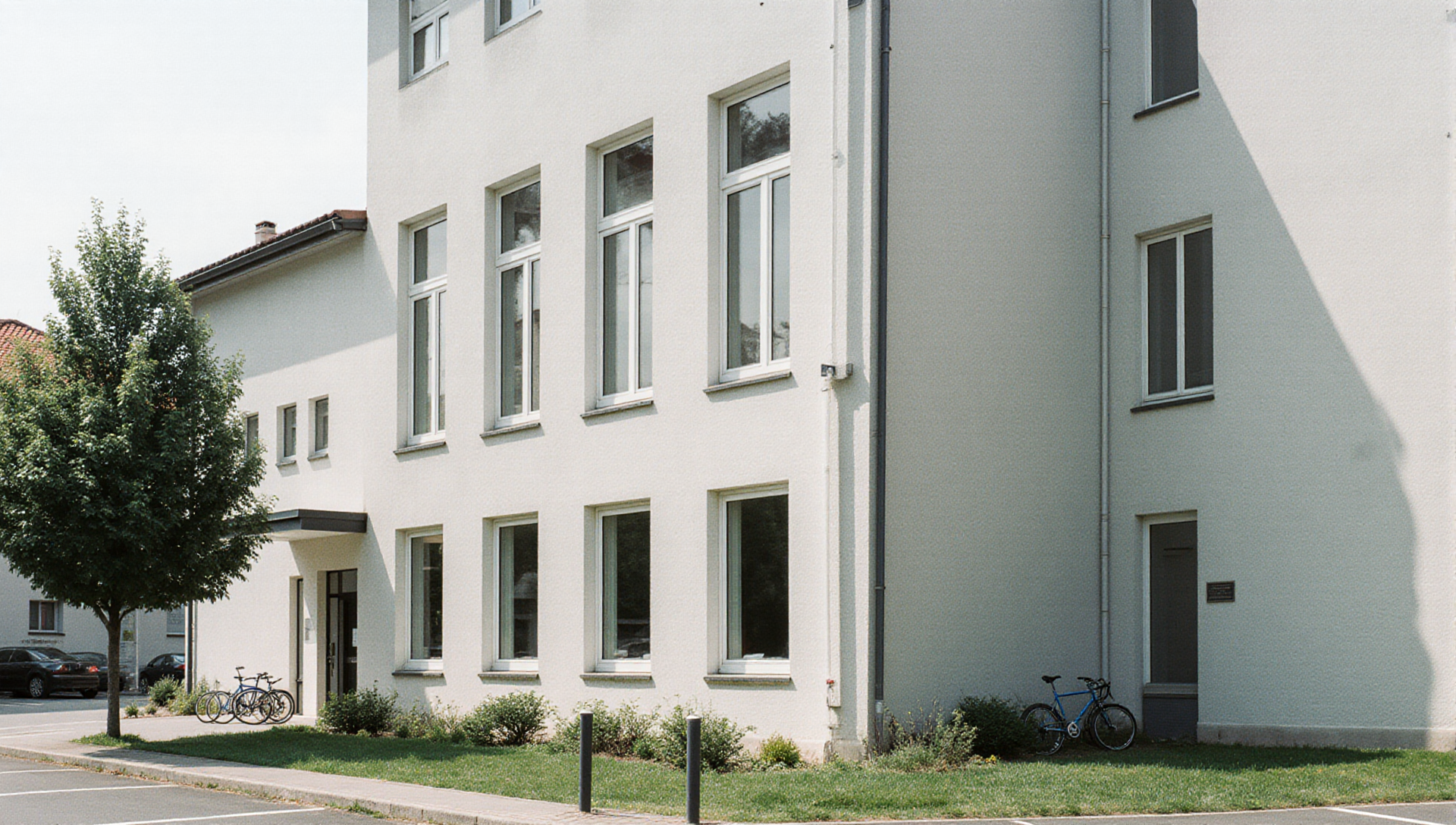 Helle Bürofassade mit Grünstreifen und Fahrradabstellplätzen